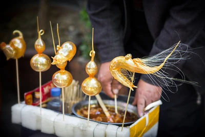 Spun sugar sculptures of pigs, gourds, and a shrimp on display at a Chinese street market.