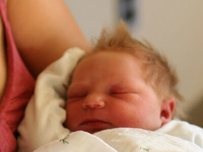 An hours-old red-haired baby in its mother's arms.