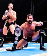 Bobby Fish and Kyle O'Reilly, two black-haired Caucasian men in black reDRagon T-shirts with the ROH World Tag Team Championship belts