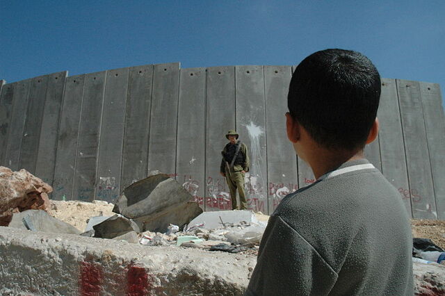 File:Boy and soldier in front of Israeli wall.jpg